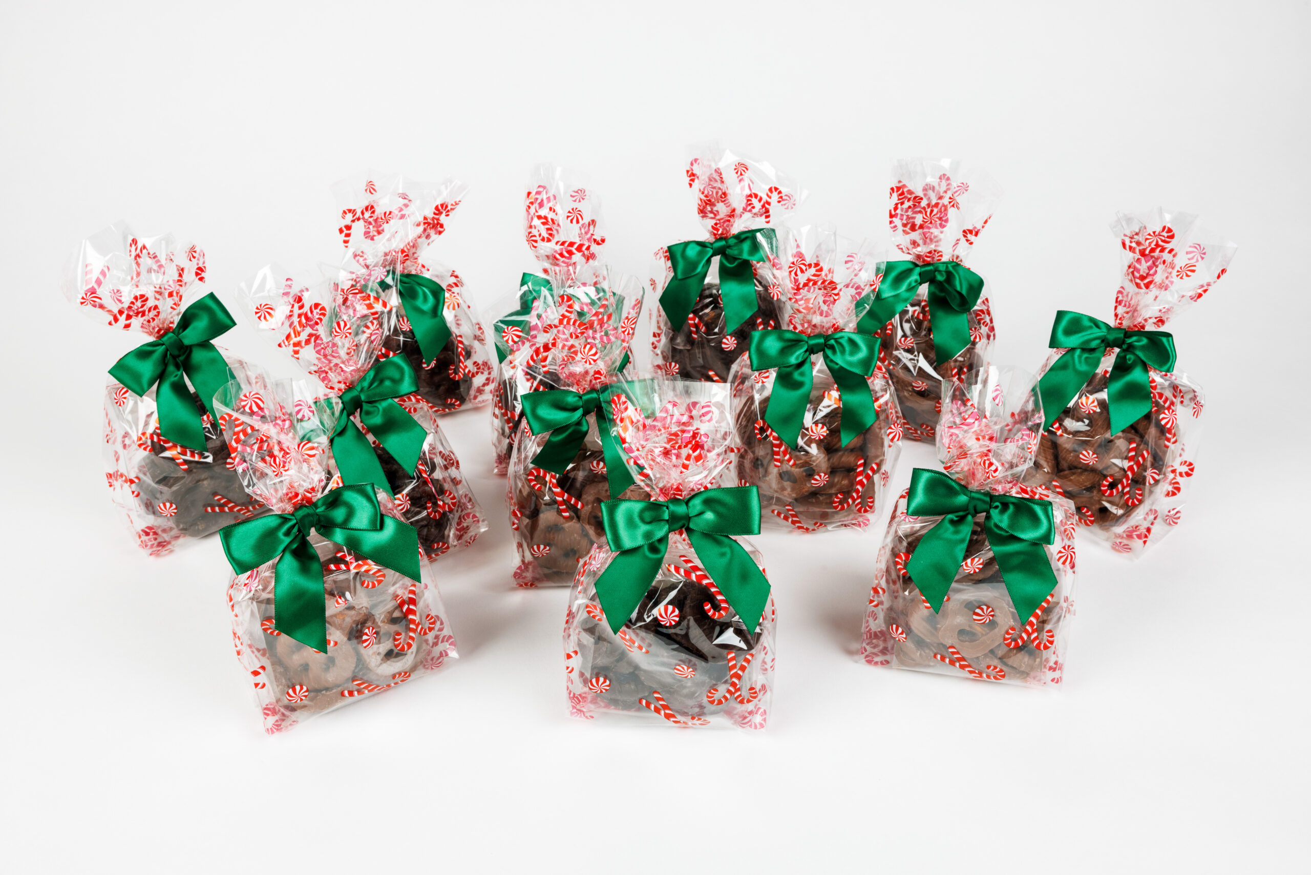 12 candy cane bags of chocolate pretzels with green bows.