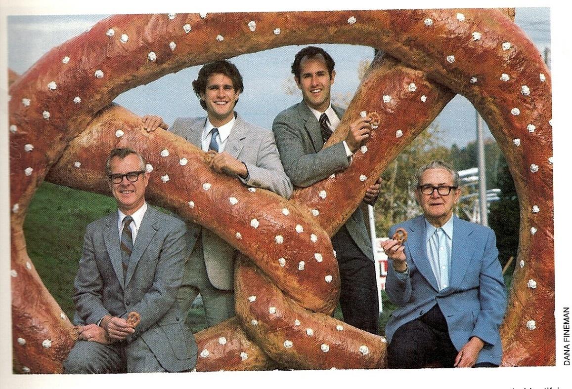A group of men posing with a giant pretzel
Description automatically generated